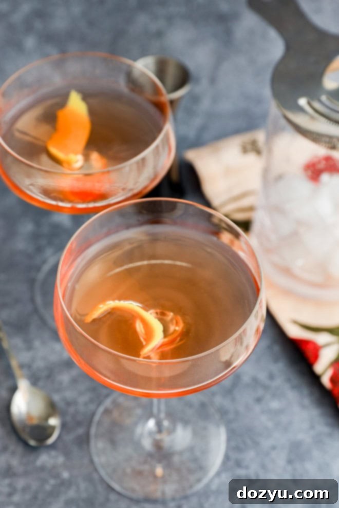 mixing glass and jigger in background with coupe glasses with pink gin cocktail