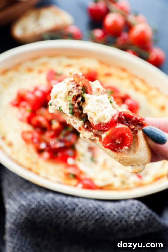 Irresistible Baked Goat Cheese Dip 8 crostini with melted cheese mixture and tomatoes and fresh herbs on it