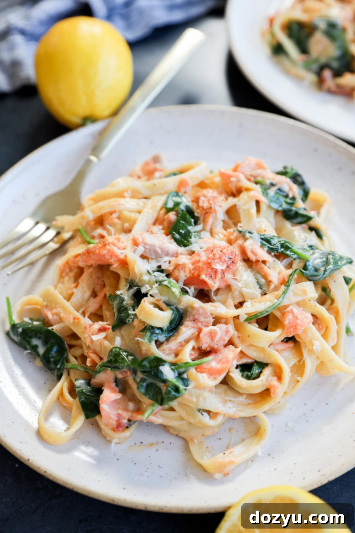 Velvety Lemon Salmon Pasta 9 easy creamy fettuccine with seafood and greens on a plate with lemons and a fork