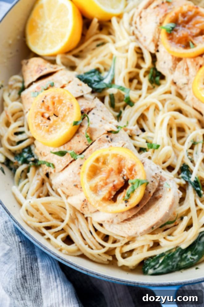 poultry sliced with citrus slices on top of creamy linguine