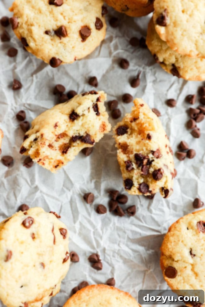 mini chocolate chip muffin in half on parchment paper with mini chocolate chips