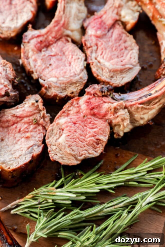 sliced rack of lamb on a cutting board with rosemary