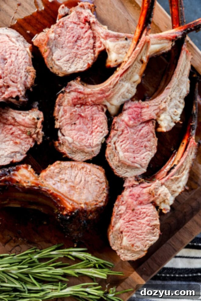 sliced BBQ rack of lamb on a cutting board, garnished with fresh rosemary for serving