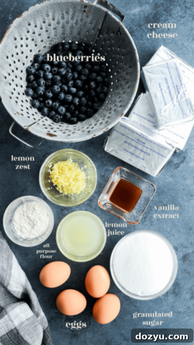 Luscious Lemon Blueberry Cheesecake 4 Key ingredients for the lemon blueberry cheesecake filling, including cream cheese, lemons, and fresh blueberries, presented in bowls with labels.
