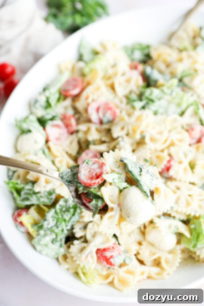 Sun-Kissed Caprese Bow Tie Salad 8 A spoonful of Caprese bow tie pasta salad, showing the perfect mix of pasta, mozzarella, tomatoes, and basil, coated in creamy dressing.