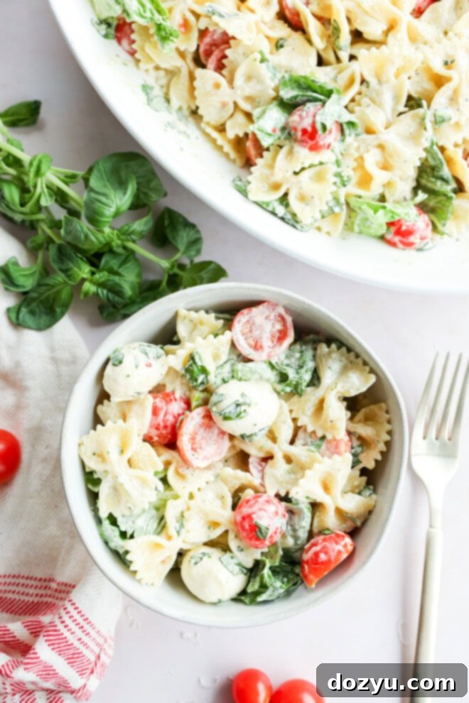 Sun-Kissed Caprese Bow Tie Salad 9 A large serving bowl filled with Caprese bow tie pasta salad, garnished with fresh basil leaves, ready for serving.
