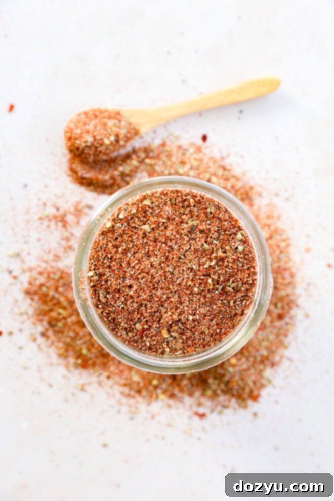 A mason jar filled with homemade Southwest spice mix, with a spoon beside it, ready for use