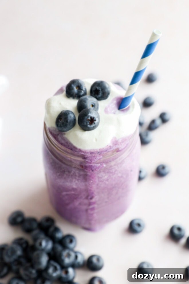 glass of sweet dessert drink with blue striped straw and fresh berries