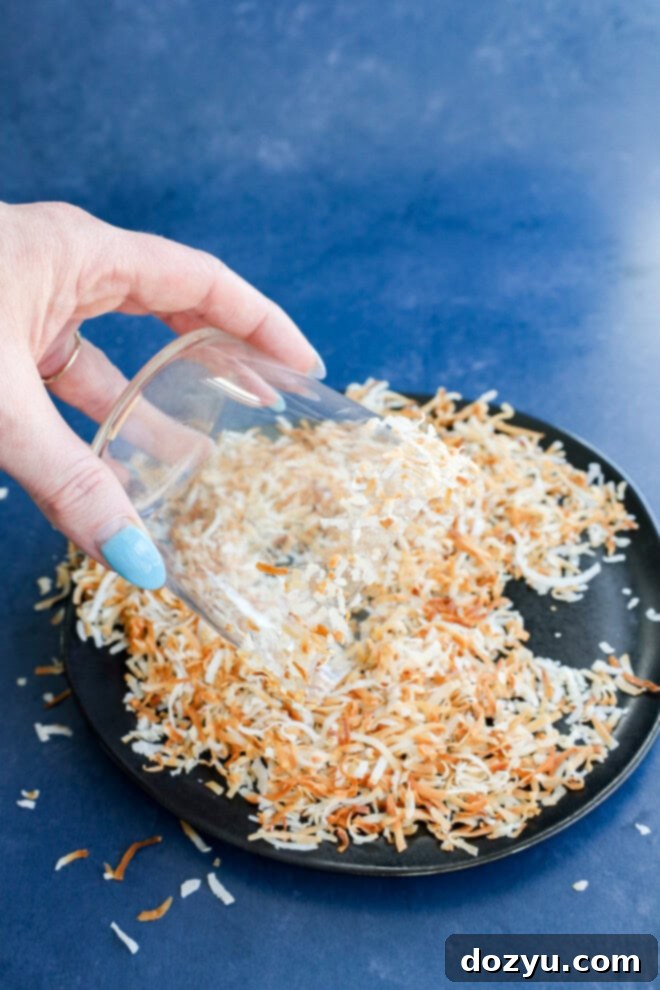 Rimming a cocktail glass with simple syrup and toasted coconut flakes for a creamy coconut margarita