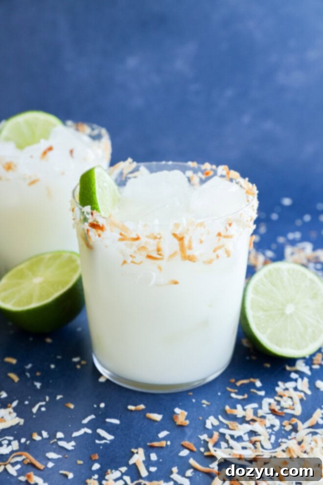 Multiple Coconut margaritas in glasses with fresh limes and toasted coconut flakes
