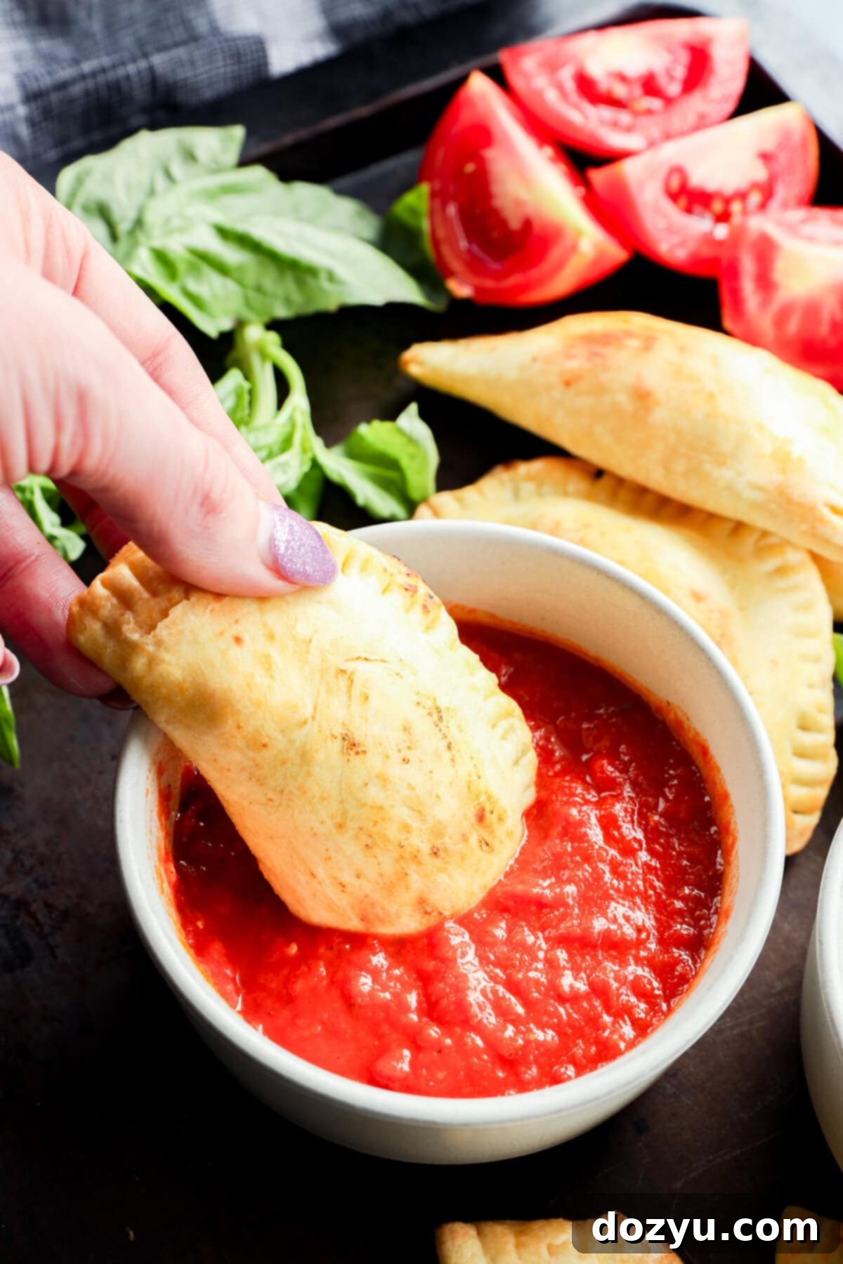 dipping pastry filled with mozzarella, basil, and tomato into marinara sauce
