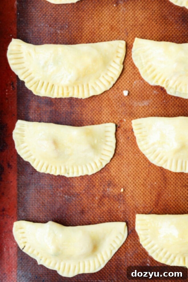 Flawless Empanada Dough Made Easy 7 formed caprese empanadas on baking sheet before baking