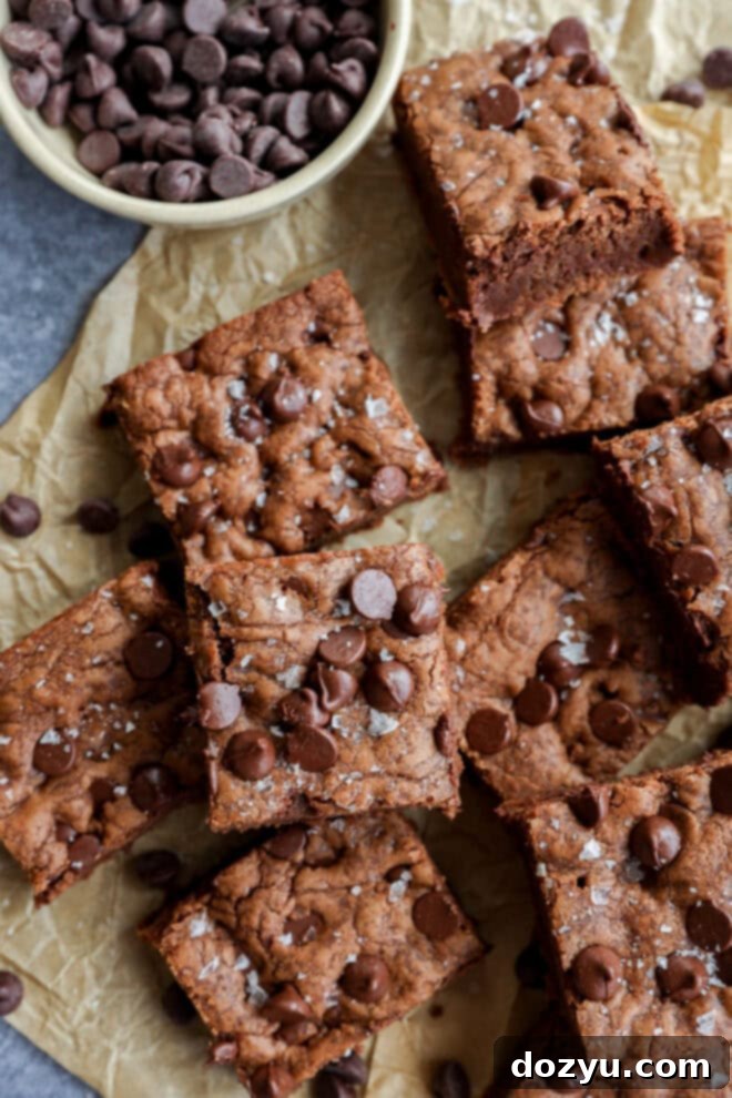 chocolate chocolate chip cookie bars with a bowl of chocolate chips on parchment paper