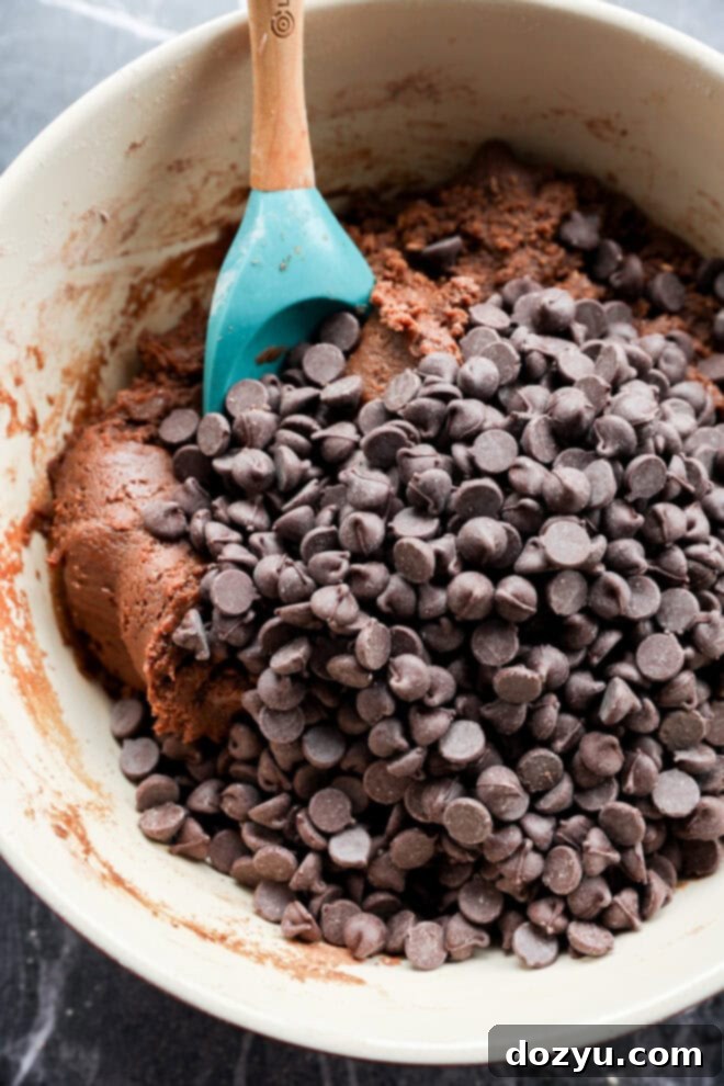 chocolate chips in cookie dough batter in a bowl with spatula