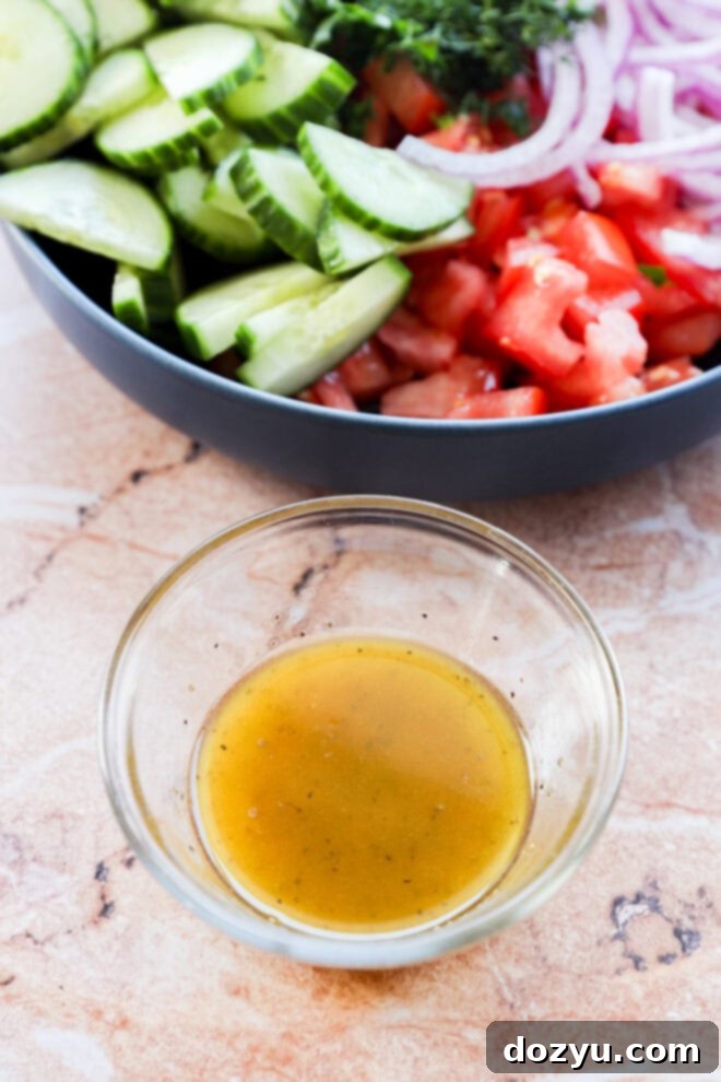 Summer Cucumber Tomato Salad 5 A red wine vinegar vinaigrette dressing in a small bowl, ready to be poured over a fresh salad.
