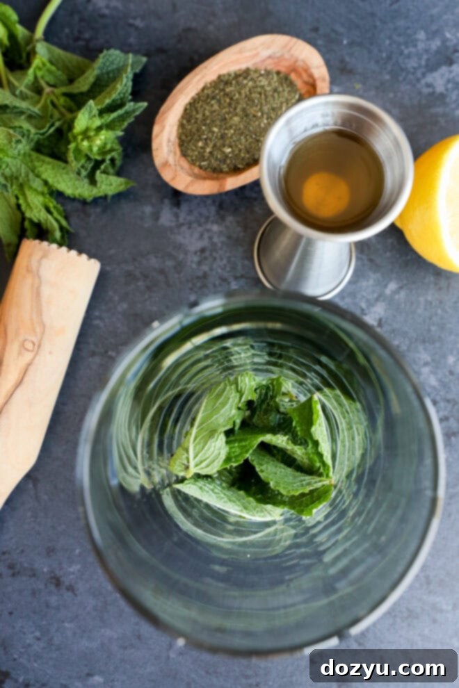 Mint leaves in shaker with lemon juice and simple syrup