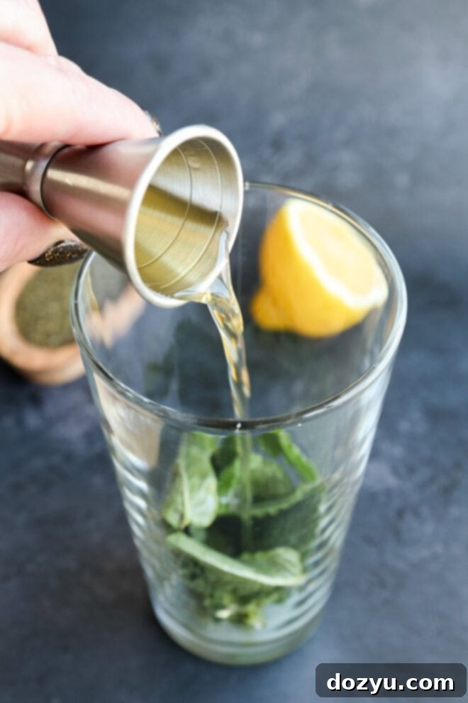 pouring green tea simple syrup into a shaker with mint leaves