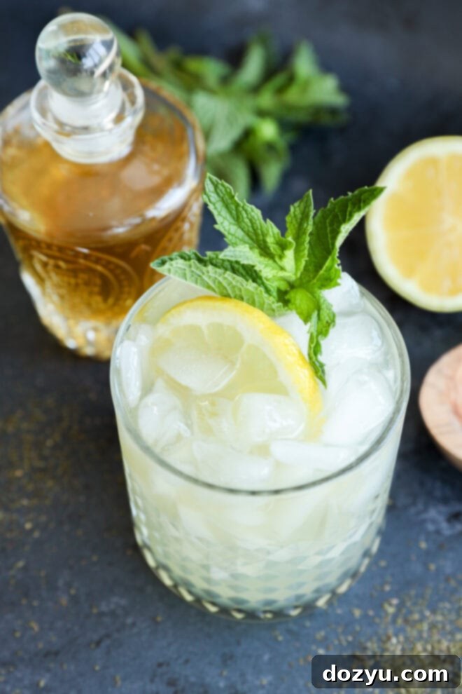 Green tea cocktail in rocks glass with lemon half and fresh mint