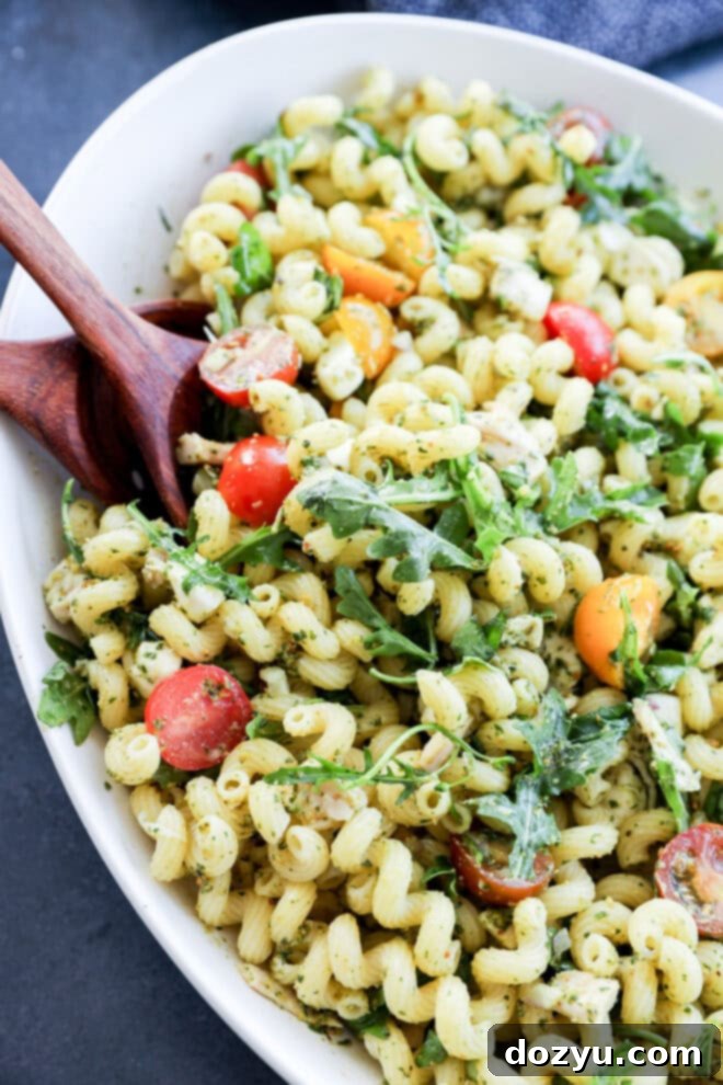 Zesty Pesto Chicken Pasta Salad 2 close up of pasta tossed with pesto and other fresh ingredients, showcasing vibrant colors and fresh basil