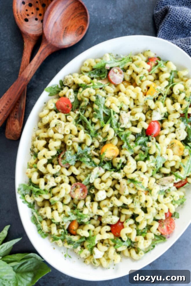 Zesty Pesto Chicken Pasta Salad 6 Easy, light, and fresh pesto chicken pasta salad recipe with fresh greens, ready to be served with wooden serving utensils.