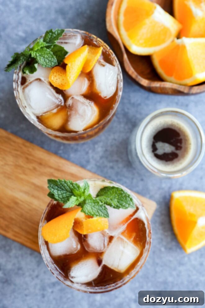 iced coffee drinks in glasses with mint and orange peel garnish