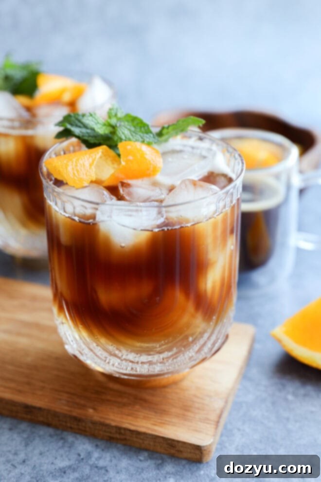 espresso tonic in glasses on wood cutting board with espresso in glass behind