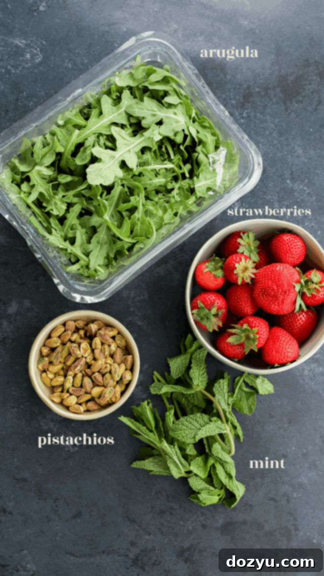 arugula strawberries pistachios and mint in bowls with text labels for salad ingredients