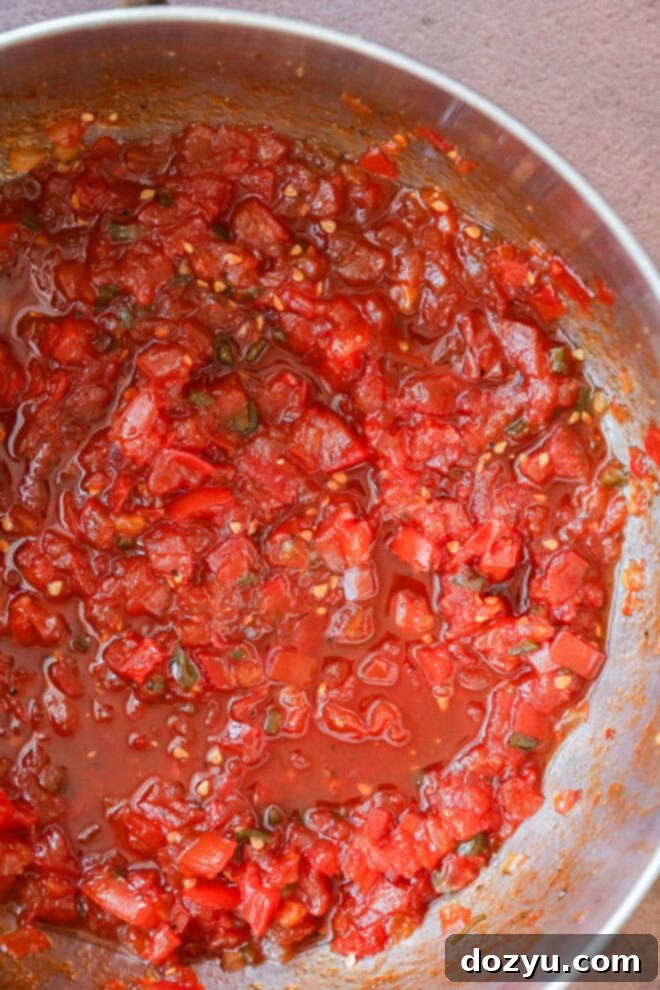 Artisan Tomato Relish 5 A close-up of freshly made tomato relish in a metal bowl, featuring chopped tomatoes, green herbs, and visible tomato juice.