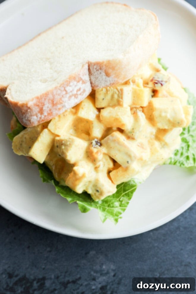 Golden Curried Chicken Salad 9 A sandwich on white bread filled with curried chicken salad—diced chicken, lettuce, and yellow curry dressing—served on a white plate.