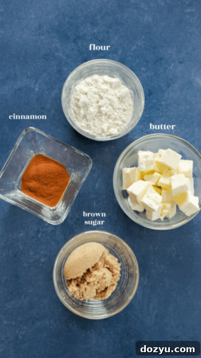 Four small bowls on a blue surface, each labeled: flour (white powder), butter (cubed), brown sugar (granulated light brown), and cinnamon—classic ingredients for delicious apple oatmeal muffins.
