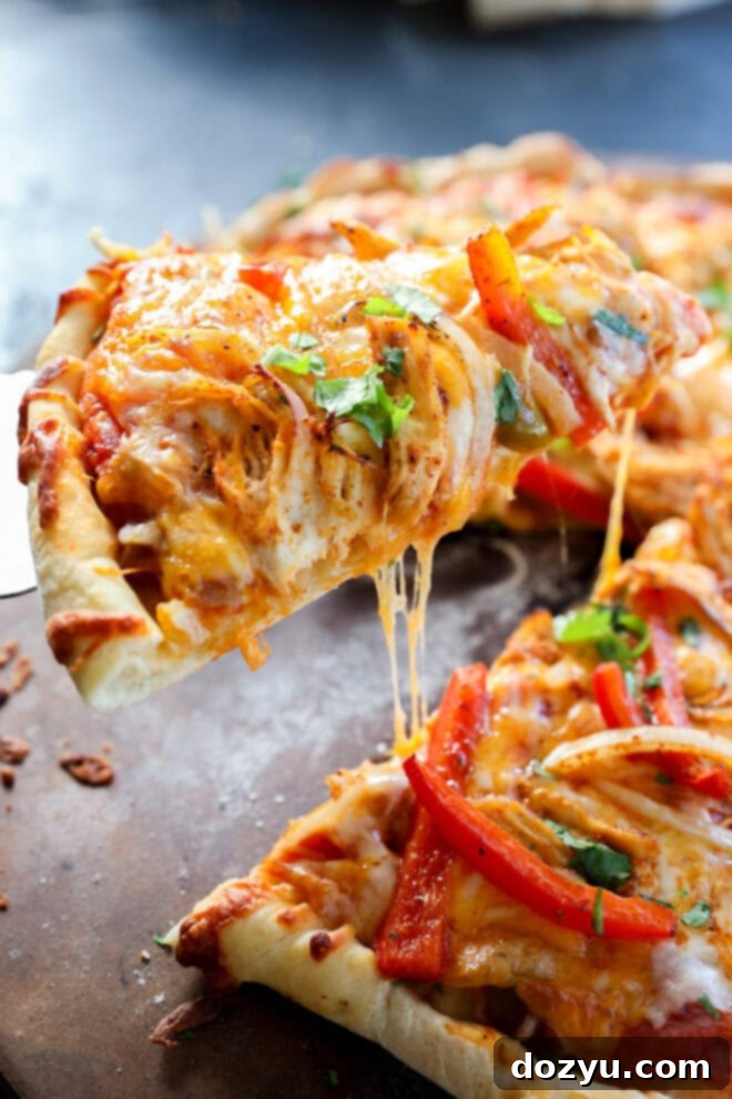 Sizzling Fajita Pizza 6 A close-up of a chicken fajita pizza slice being lifted, topped with melted cheese, chicken, red bell peppers, onions, and sprinkled with fresh herbs. The crust looks golden and crispy, with cheese stretching as the slice is pulled away.