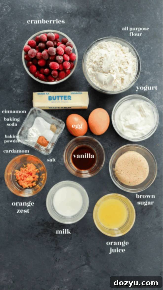 Ingredients for orange cranberry muffins laid out on a dark surface.