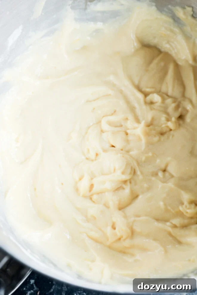 Lemon Ricotta Bliss Cake 4 Close-up of a bowl containing smooth, creamy lemon ricotta cake batter, with visible swirls and folds in the mixture.