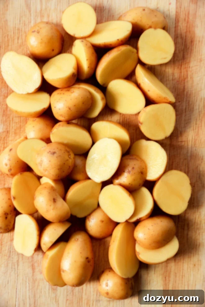 Lemon Herb Roasted Chicken and Potatoes 7 A pile of small yellow potatoes, some whole and some cut in half, arranged on a wooden cutting board