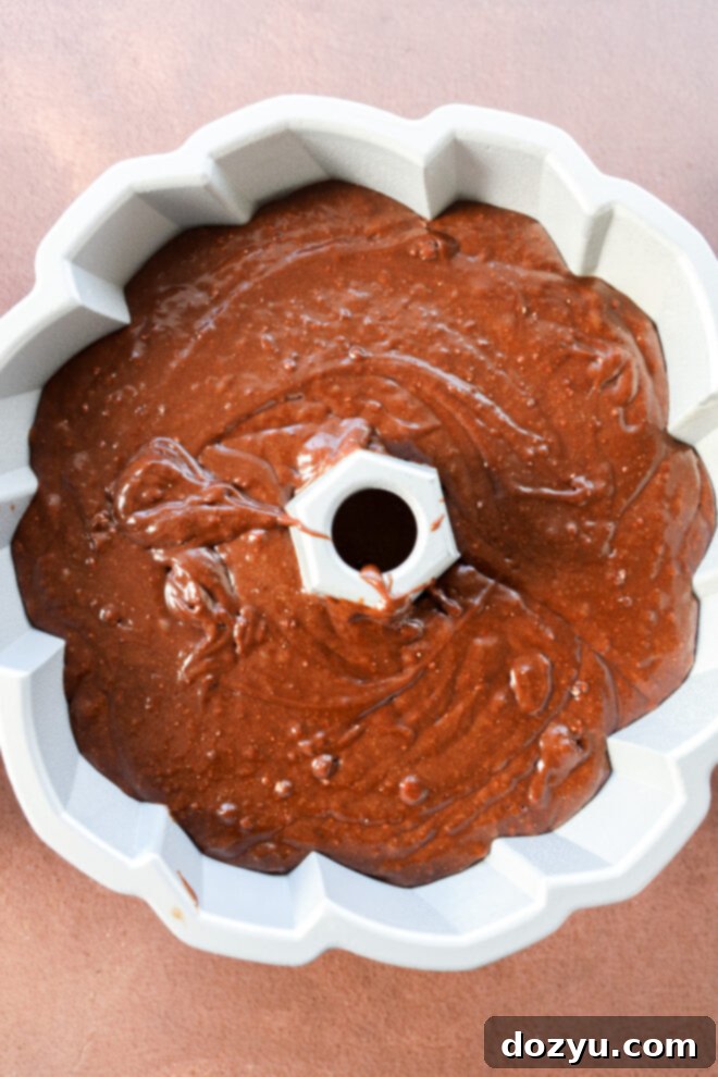 Brownie cake batter poured into a white Bundt pan.