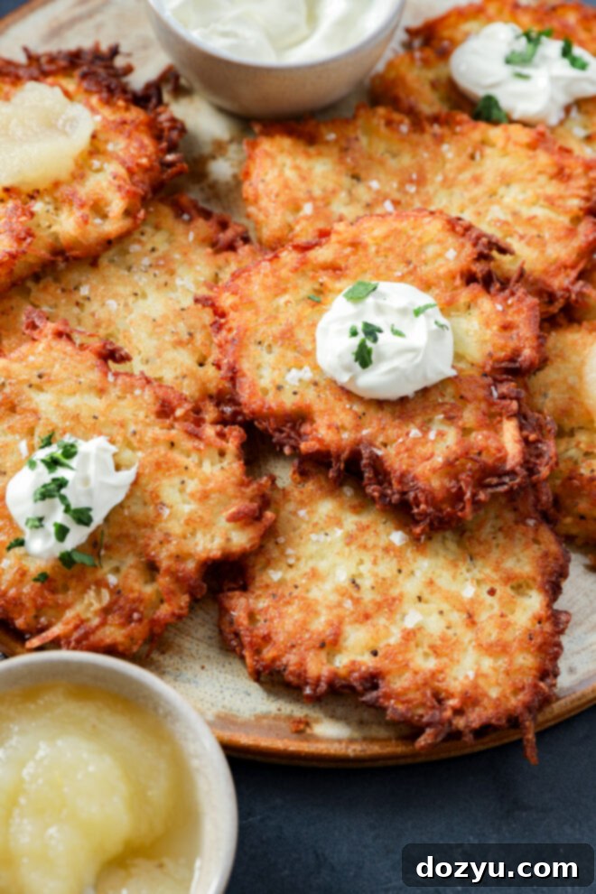 A plate of crispy Jewish latkes with sour cream and herbs.