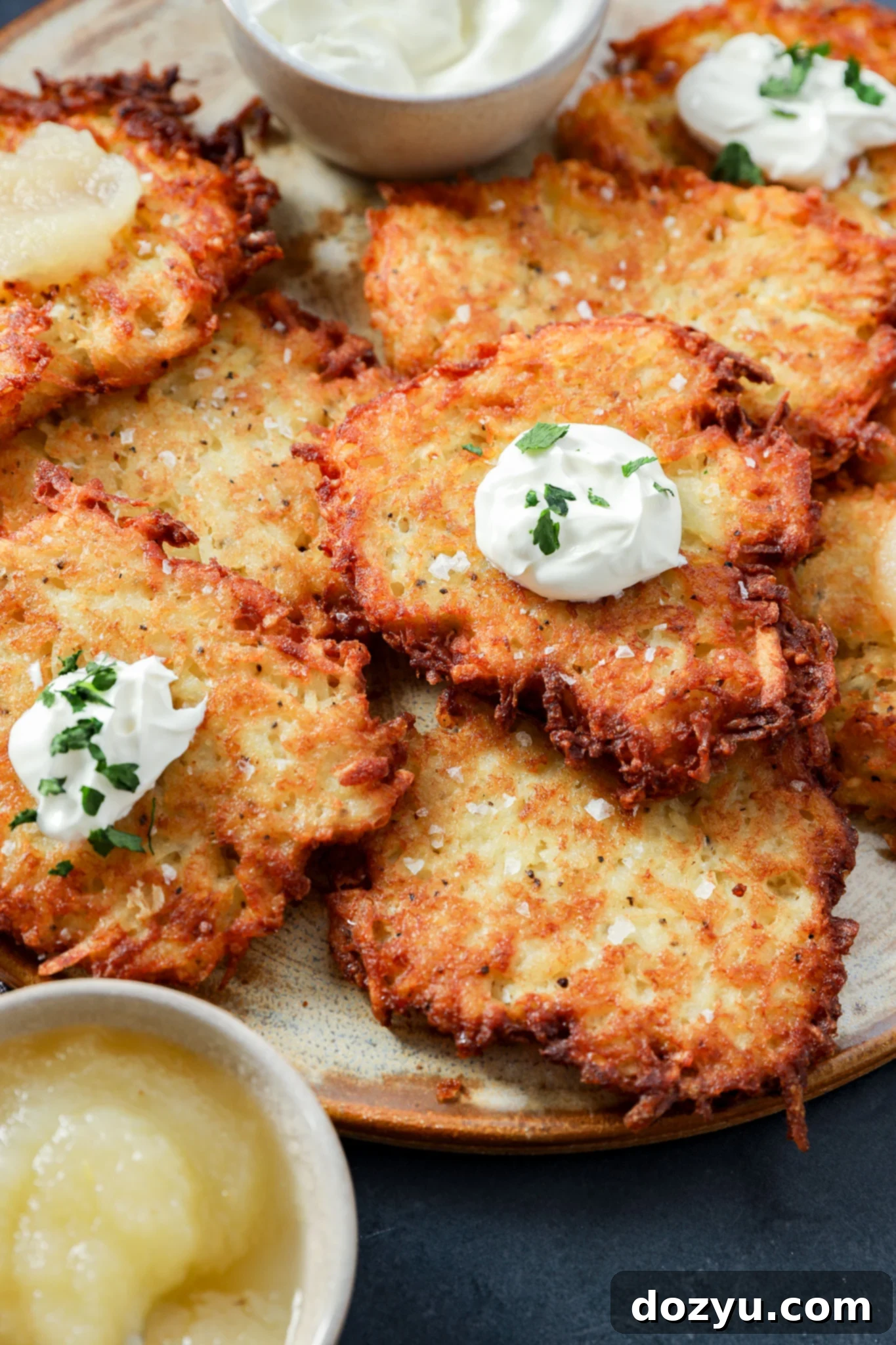 A plate of crispy Jewish latkes topped with sour cream and herbs